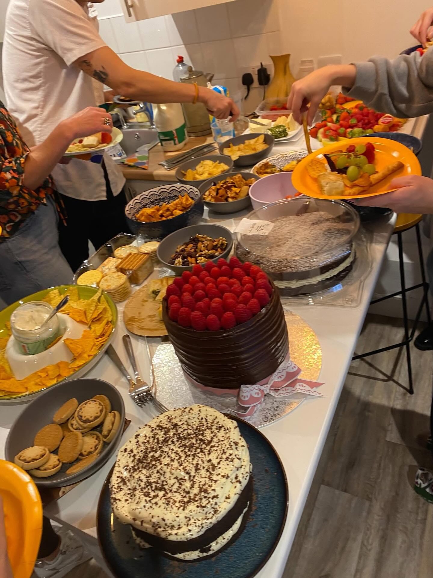 A shared table of cakes, fruit and treats