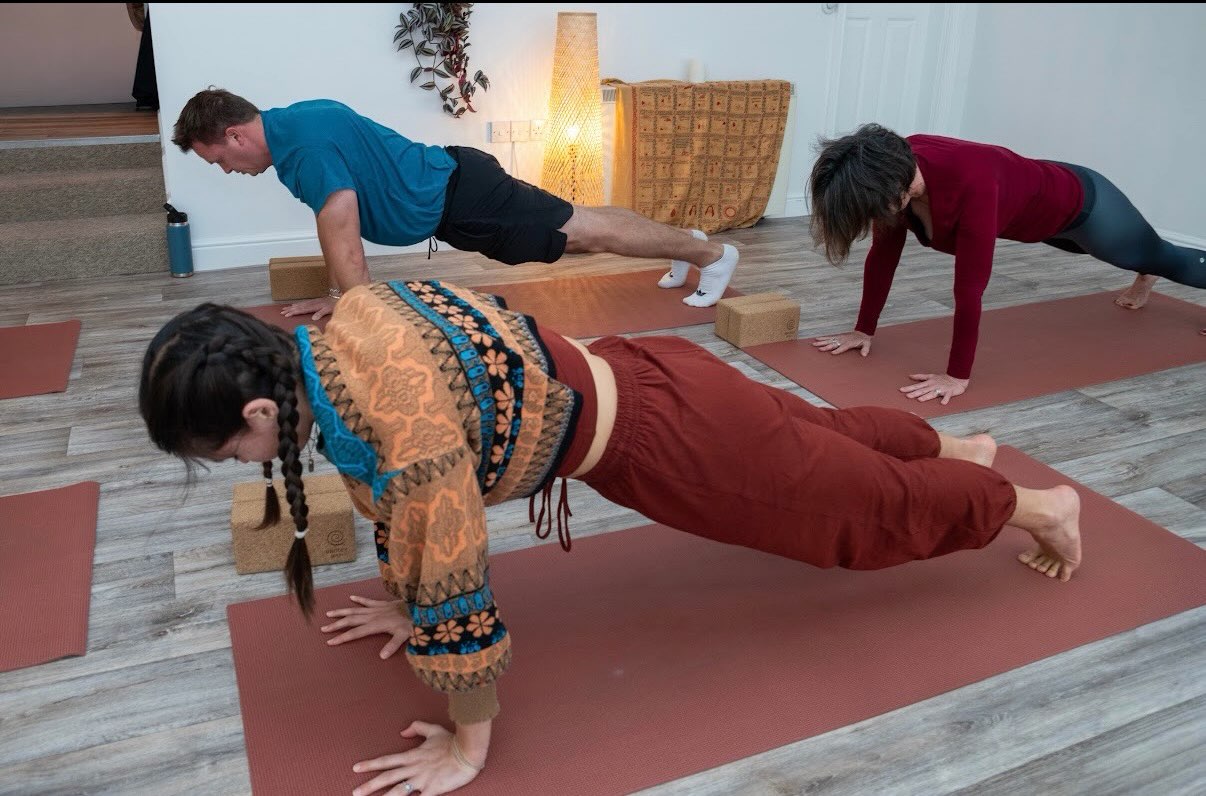 A man and women holding a plank on their mats during a class
