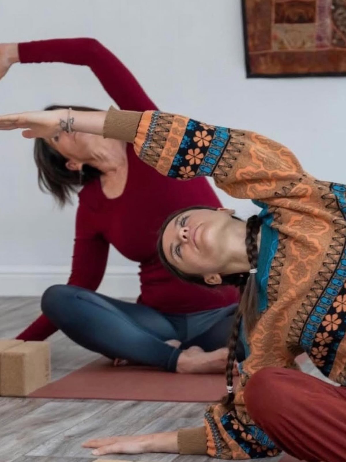Two people in a side stretch on mats in the studio
