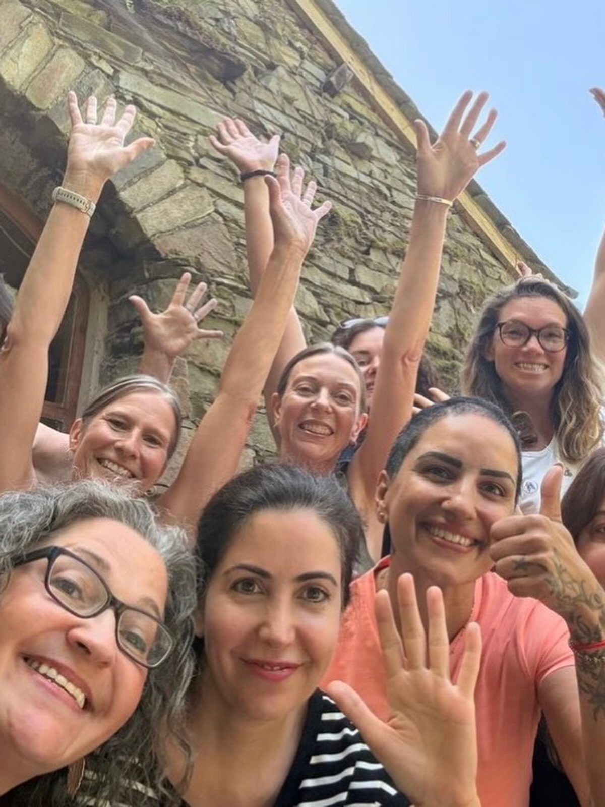 Smiling students outdoors with their hands in the air